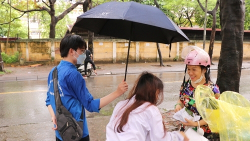 Thi tốt nghiệp THPT: Tình nguyện viên che ô giúp thí sinh ăn sáng trước khi vào thi